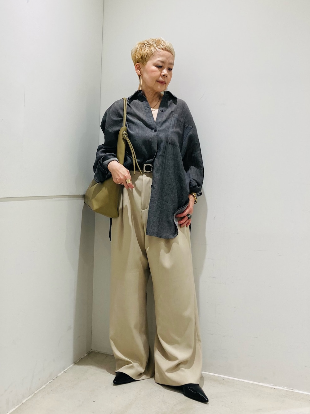 ブラック系のシャツ/ブラウス、ベージュ系のスラックス、ブラック系のパンプスを着用したレディースの春コーディネートの1枚目の写真