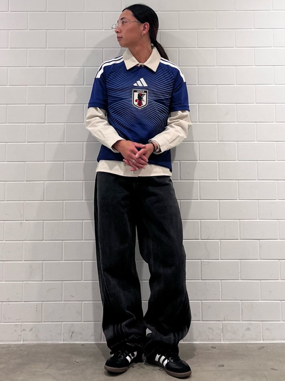 ブラック系のデニムパンツ、ブルー系のTシャツ/カットソー、ブラック系のスニーカーを着用したメンズの秋コーディネートの1枚目の写真