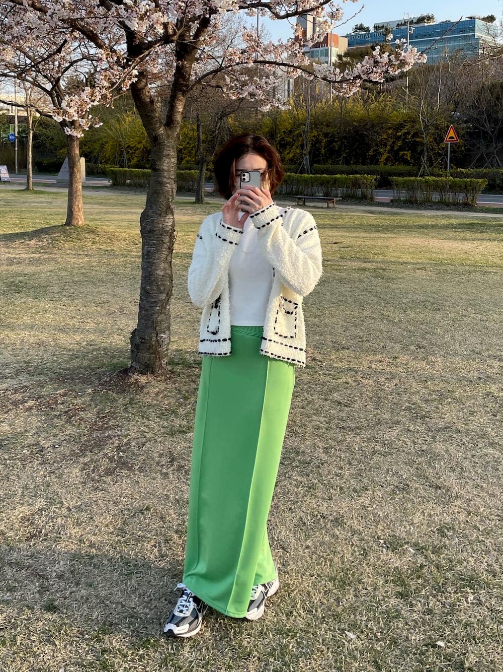 グリーン系のスカートを着用したレディースの春コーディネートの1枚目の写真