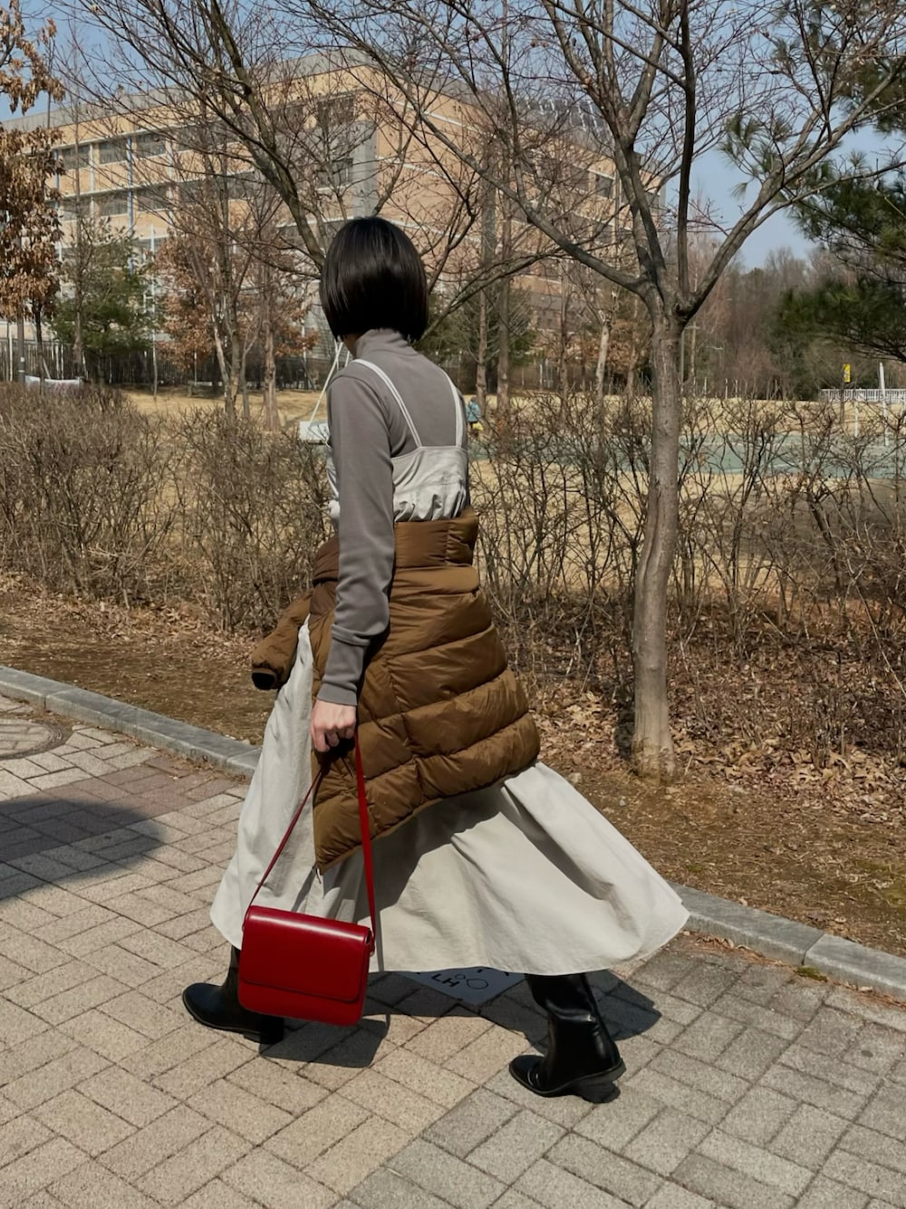 グレー系のワンピース、レッド系のショルダーバッグ、ブラック系のブーツを着用したレディースの春コーディネートの1枚目の写真