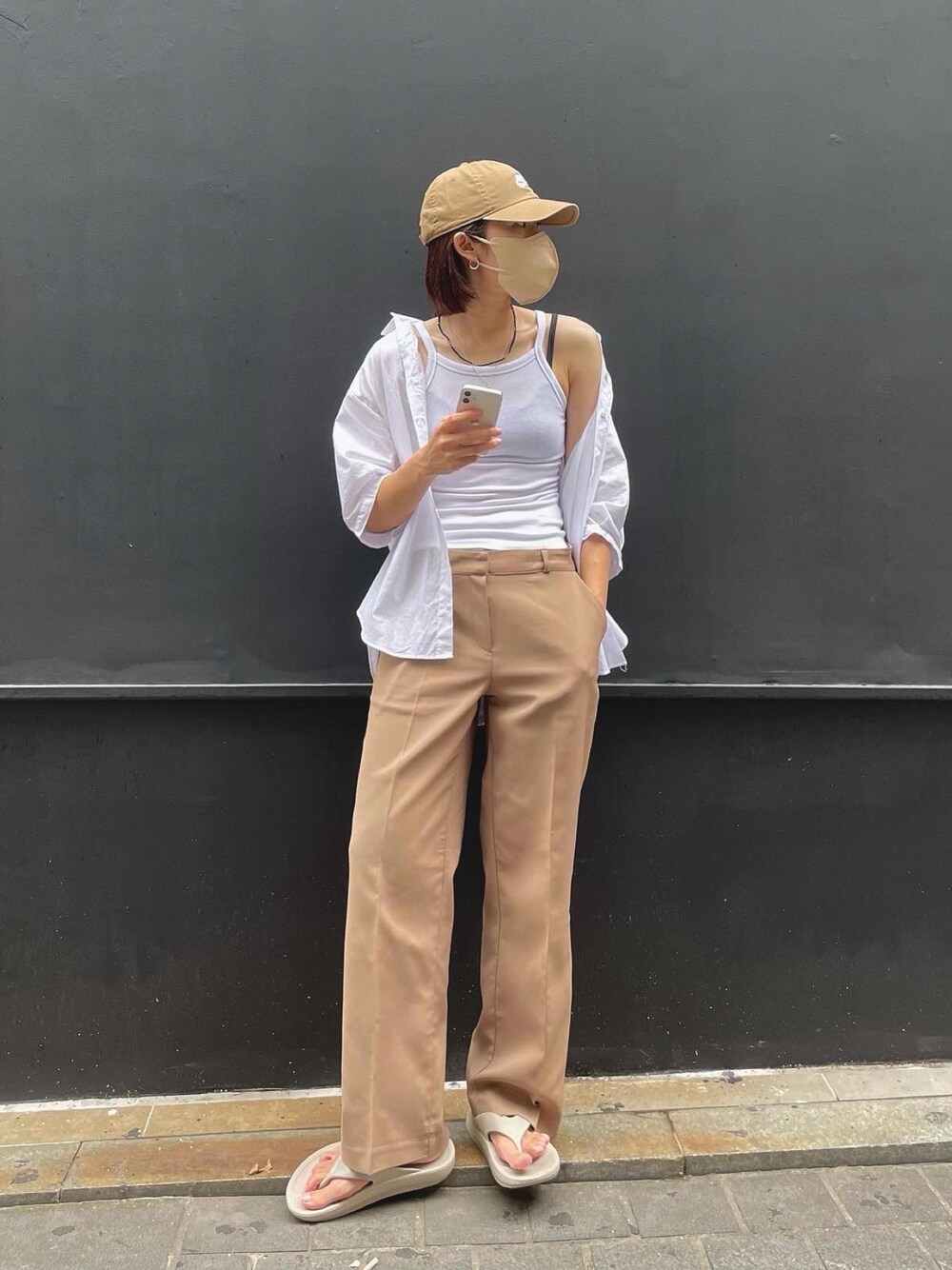 ホワイト系のキャミソール、ベージュ系のスラックス、ベージュ系のサンダルを着用したレディースの夏コーディネートの1枚目の写真