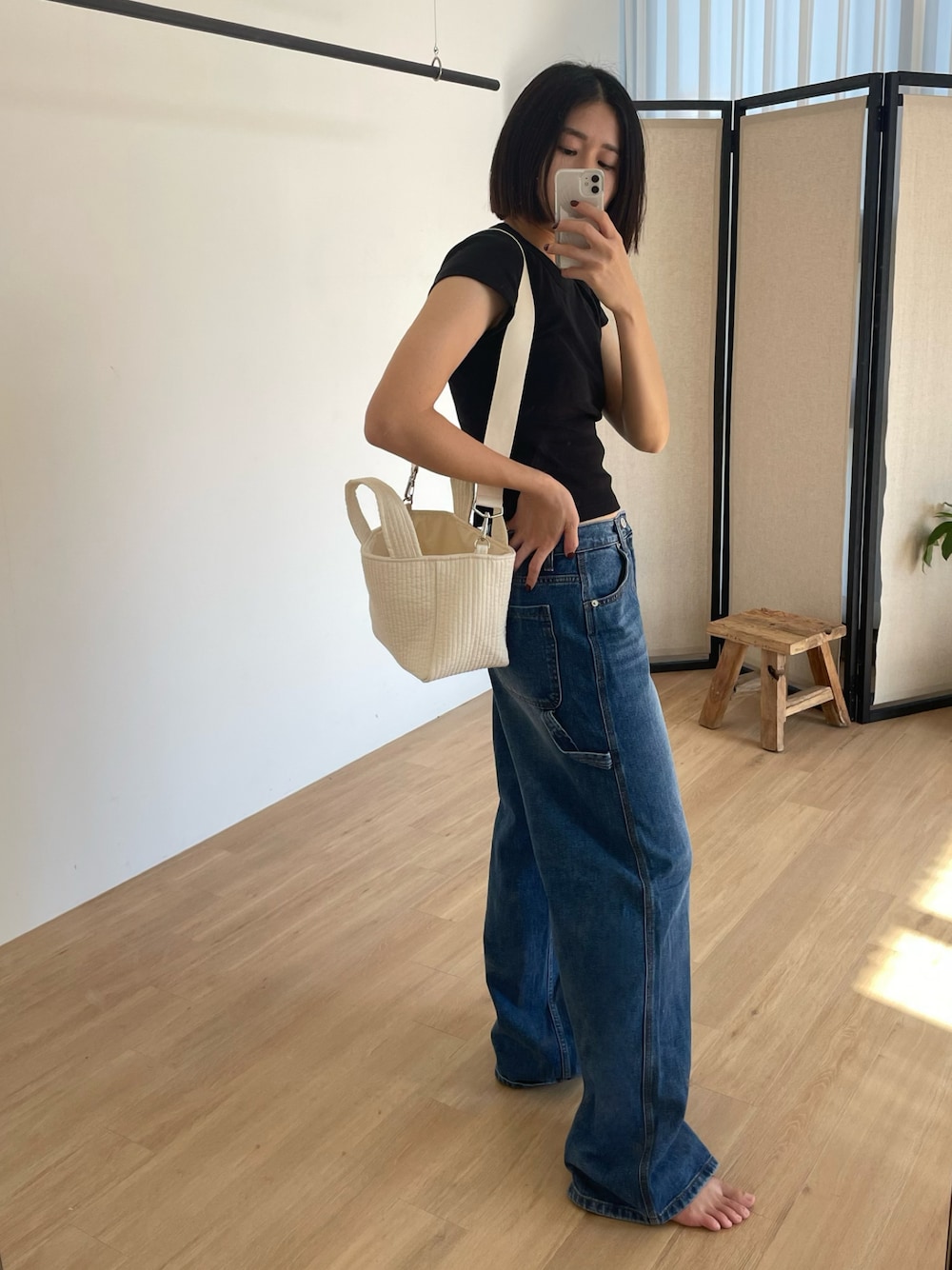 ホワイト系のショルダーバッグ、ブルー系のデニムパンツを着用したレディースの夏コーディネートの1枚目の写真