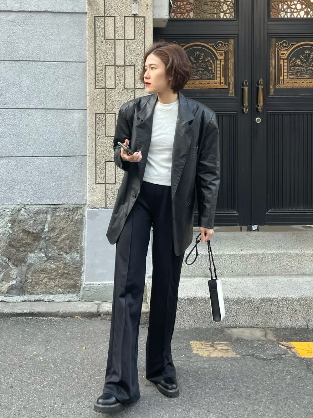 ブラック系のテーラードジャケット、ホワイト系のショルダーバッグ、ブラック系のスウェットパンツを着用したレディースの冬コーディネートの1枚目の写真