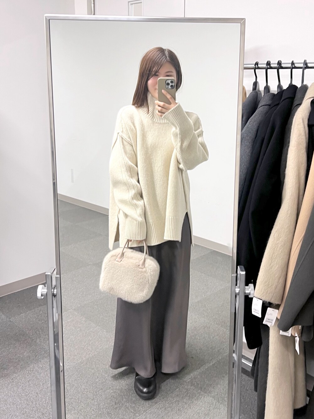 ベージュ系のボストンバッグ、ホワイト系のニット/セーター、ブラウン系のスカートを着用したレディースの秋コーディネートの1枚目の写真