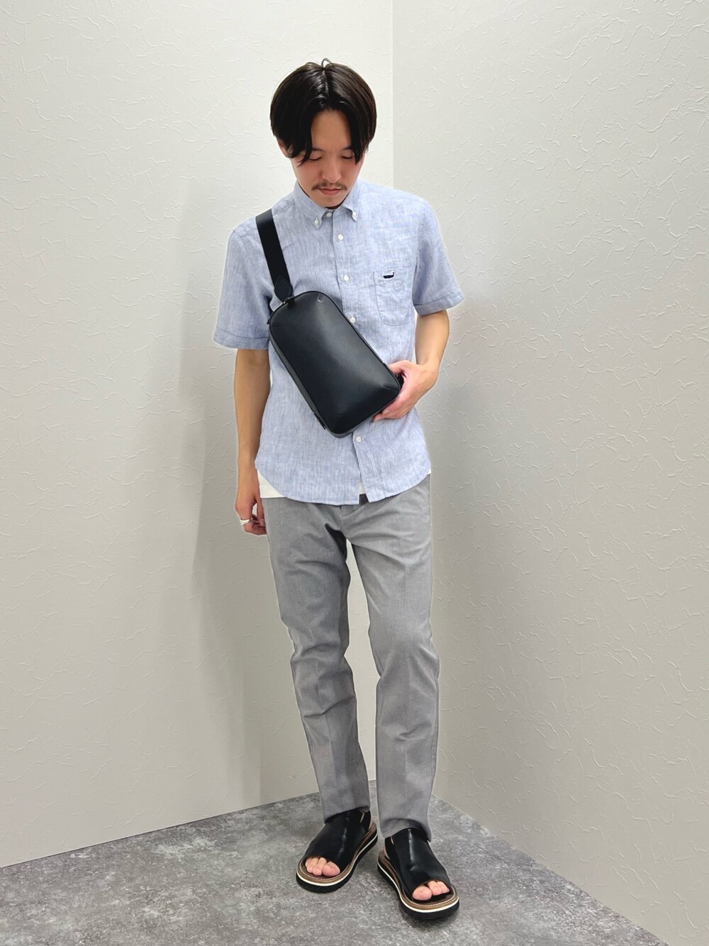ブルー系のシャツ/ブラウス、ブラック系のボディバッグ/ウエストポーチ、グレー系のチノパンツを着用したメンズの春コーディネートの1枚目の写真