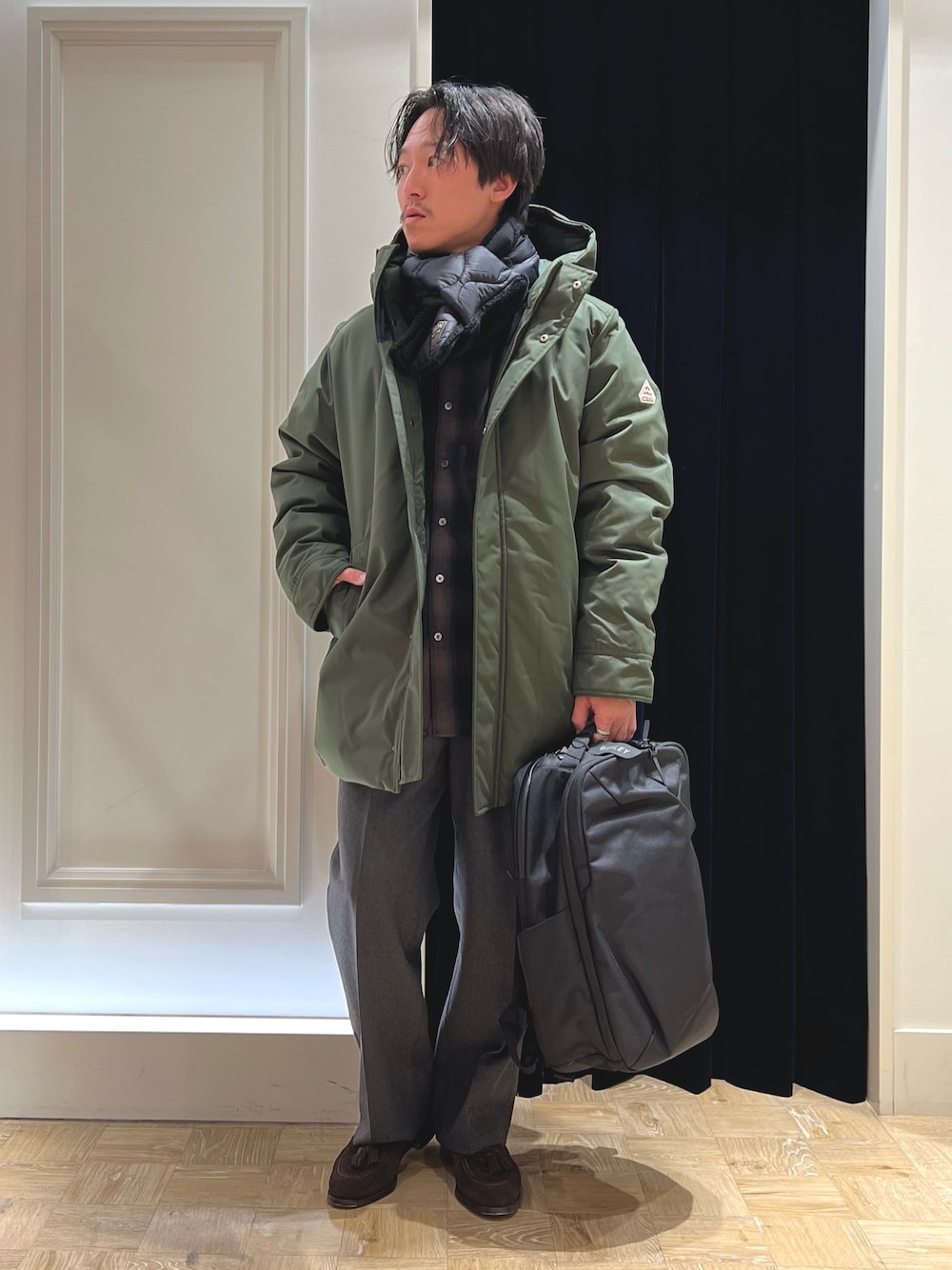 グリーン系のシャツ/ブラウス、ブラック系のバックパック/リュック、グリーン系のダウンジャケット/コートを着用したメンズの冬コーディネートの1枚目の写真