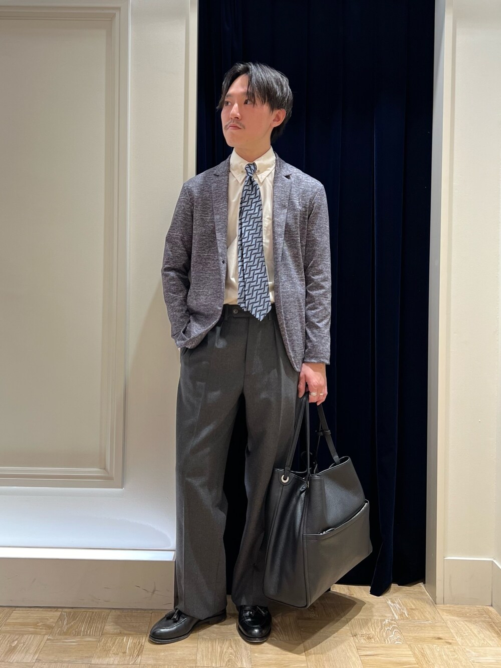 グレー系のカーディガン/ボレロ、ブルー系のネクタイ、ブラック系のトートバッグを着用したメンズの冬コーディネートの1枚目の写真