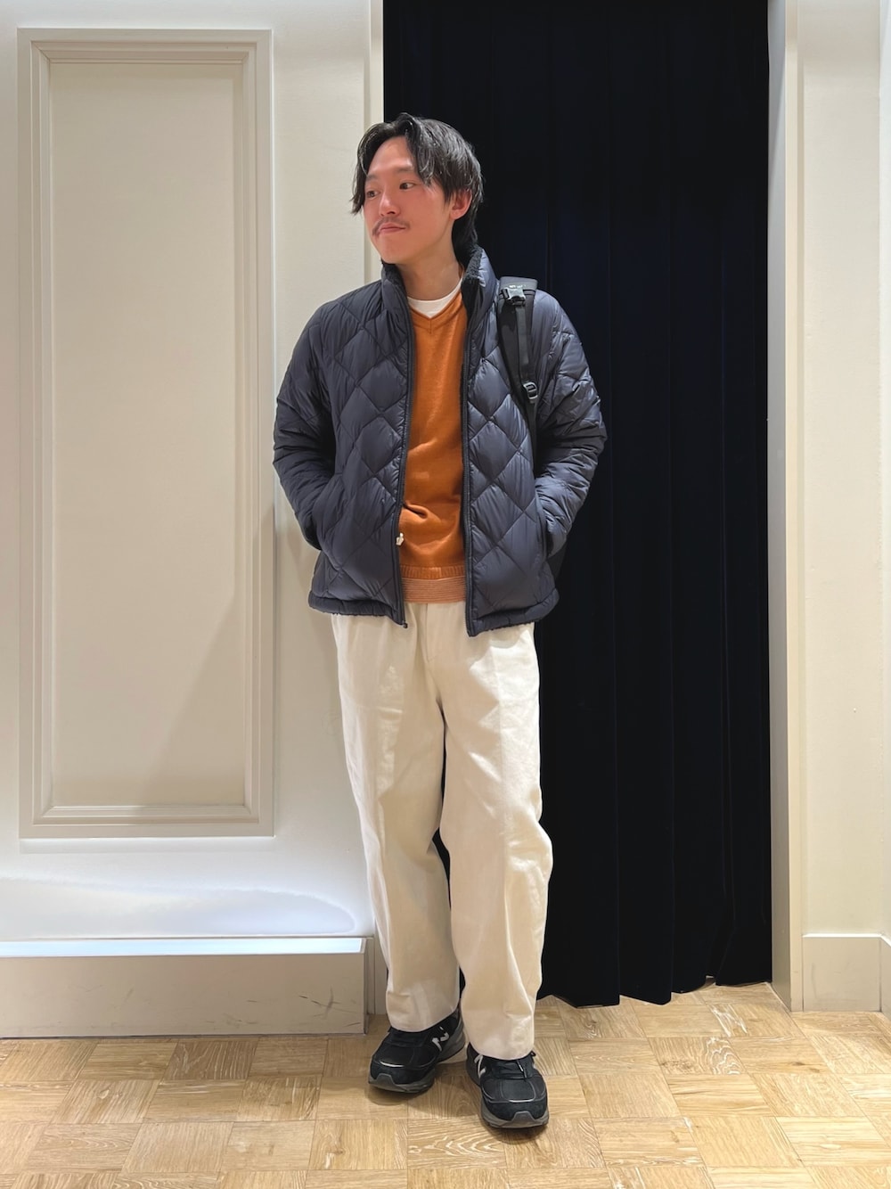 ブルー系のダウンジャケット/コート、イエロー系のニット/セーター、ブラック系のバックパック/リュックを着用したメンズの冬コーディネートの1枚目の写真