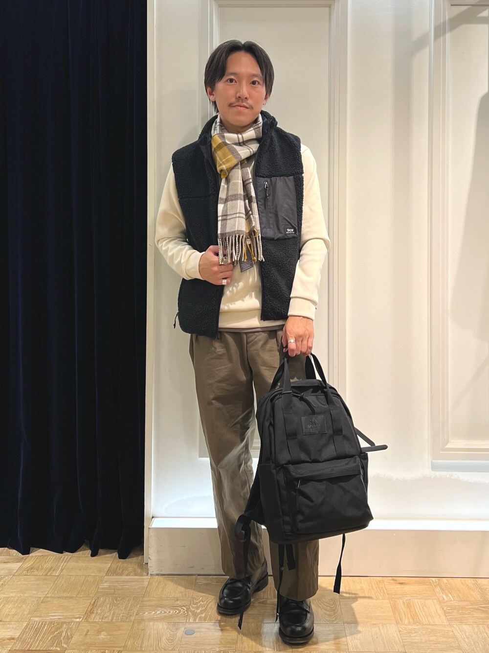 ブラック系のダウンベスト、ホワイト系のTシャツ/カットソー、ブラック系のバックパック/リュックを着用したメンズの秋コーディネートの1枚目の写真