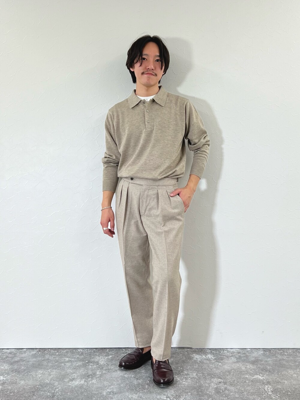 ベージュ系のスラックス、ブラウン系のローファー、ベージュ系のニット/セーターを着用したメンズの冬コーディネートの1枚目の写真