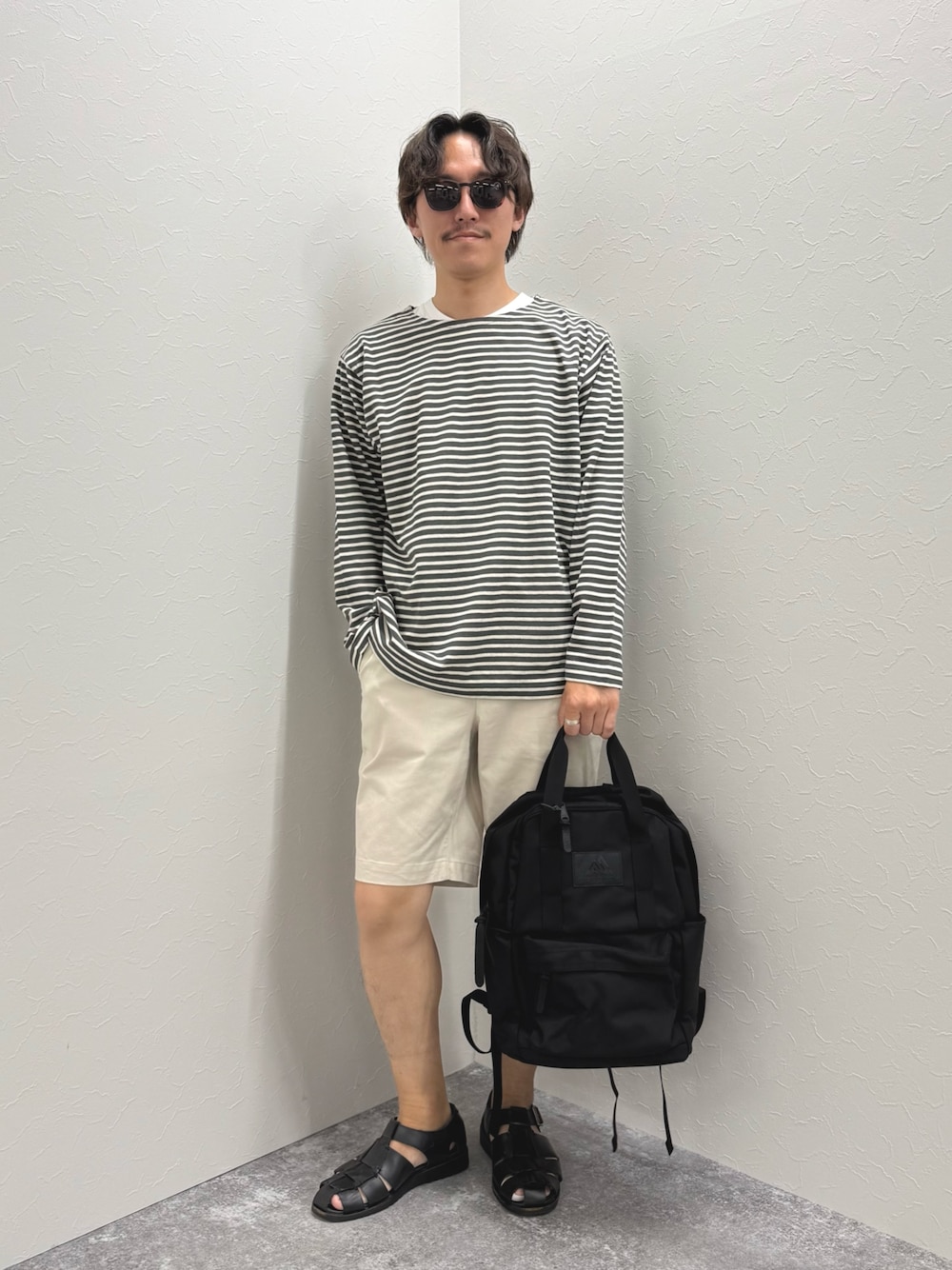 グレー系のTシャツ/カットソー、ホワイト系のその他パンツ、ブラック系のバックパック/リュックを着用したメンズの春コーディネートの1枚目の写真