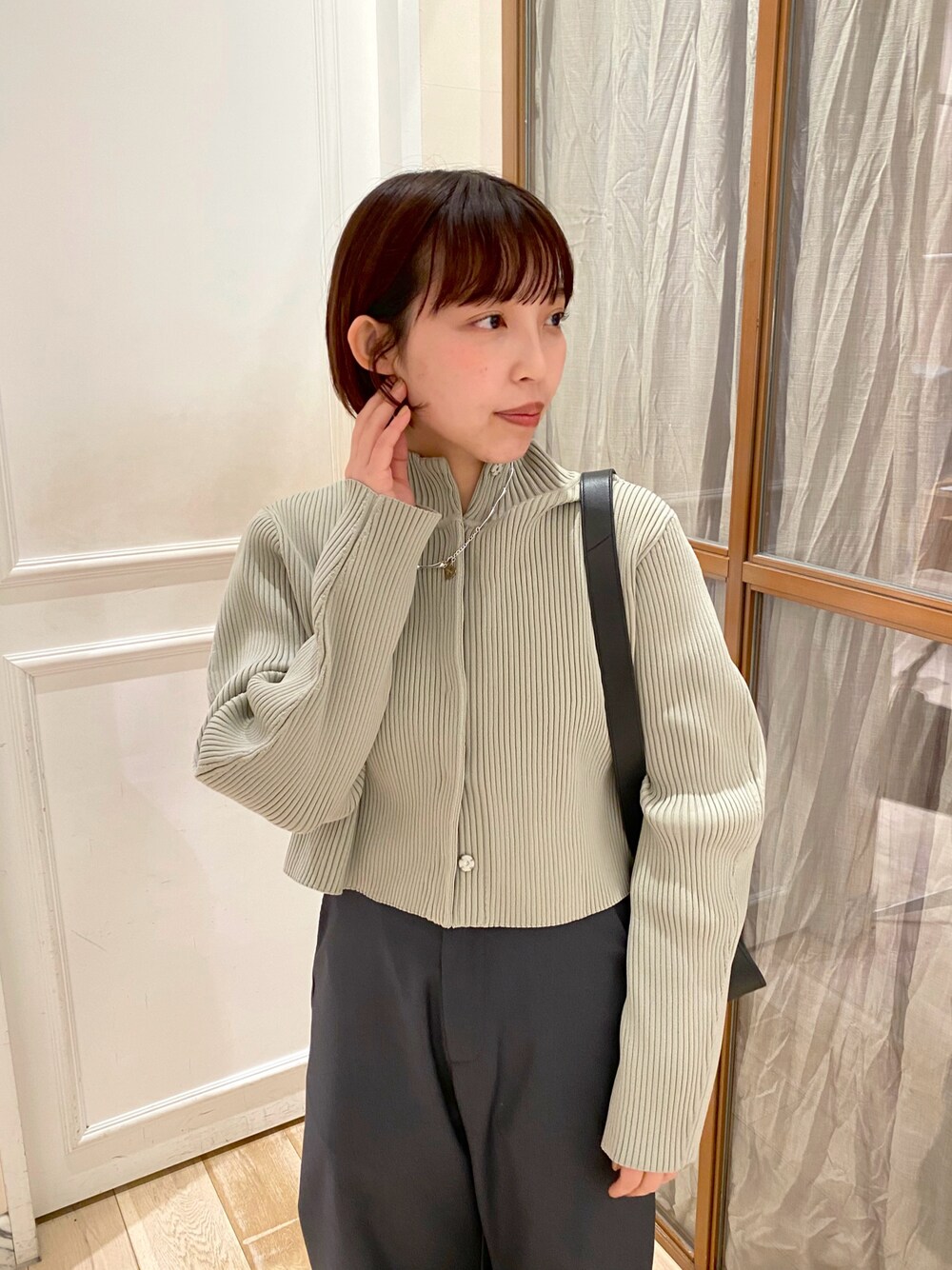 グリーン系のカーディガン/ボレロ、グレー系のスラックスを着用したレディースの冬コーディネートの1枚目の写真