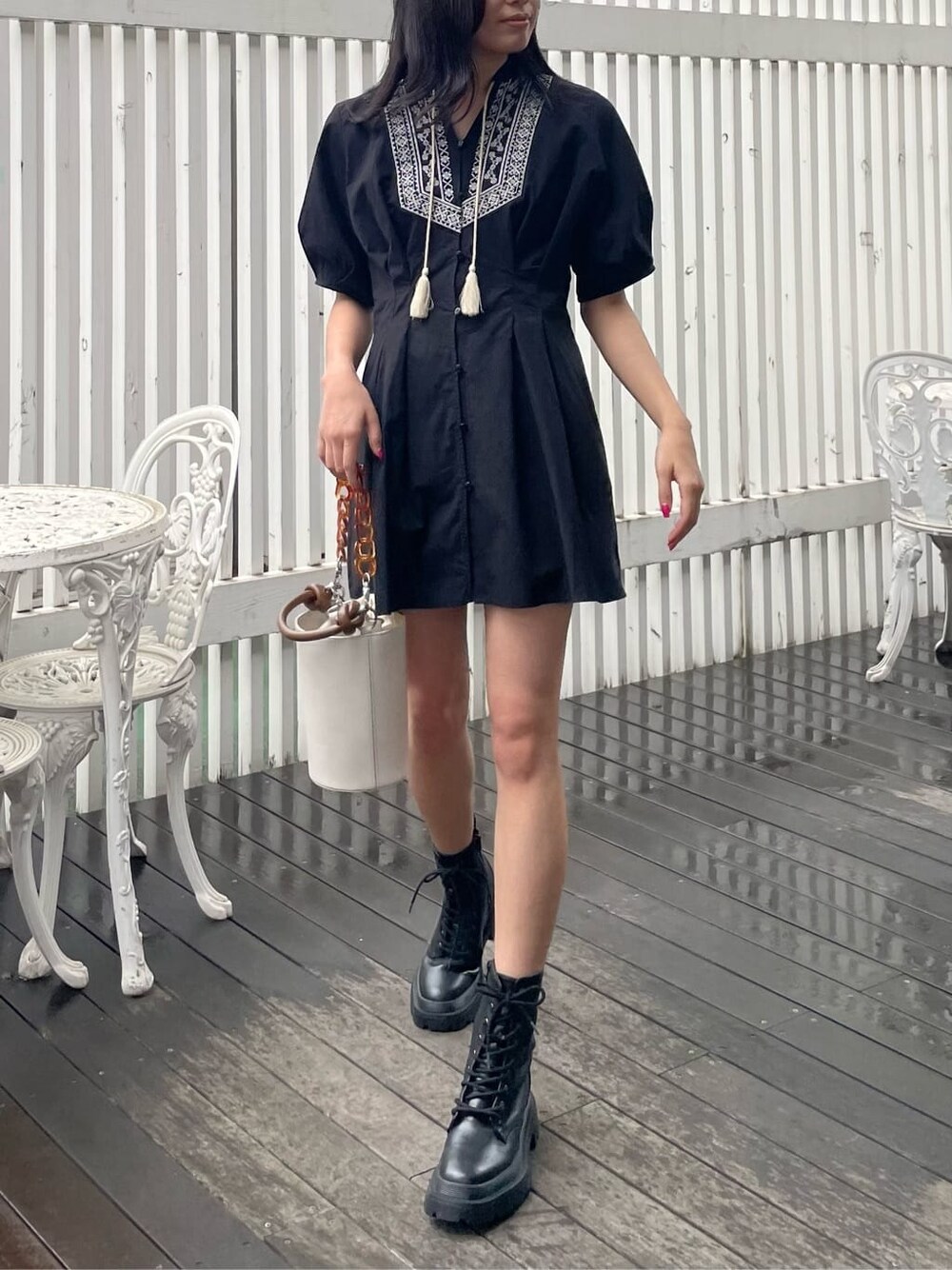 ブラック系のブーツ、ブラック系のワンピース、ホワイト系のショルダーバッグを着用したレディースの春コーディネートの1枚目の写真