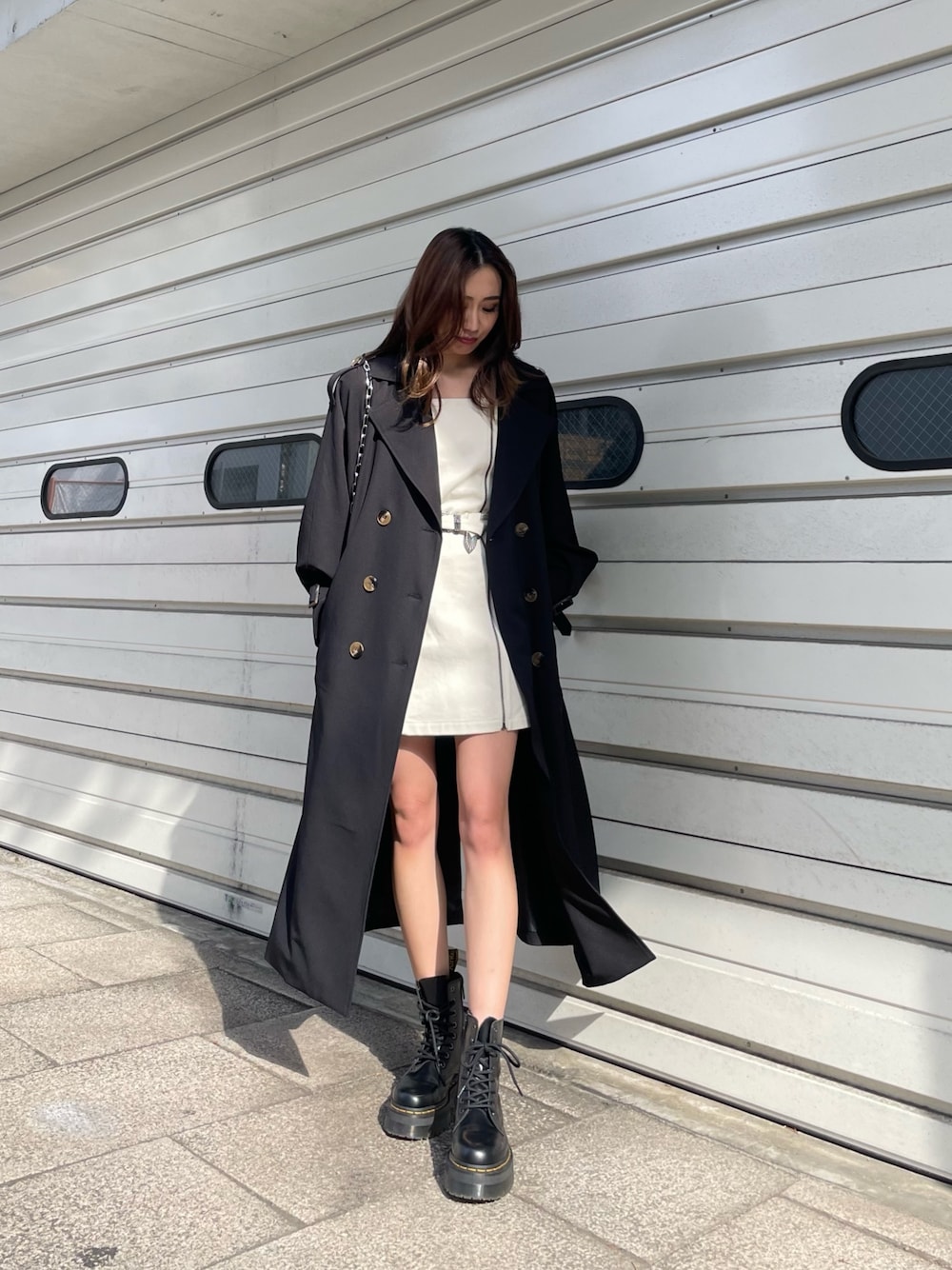 ブラック系のショルダーバッグ、ブラック系のトレンチコート、ホワイト系のワンピースを着用したレディースの冬コーディネートの1枚目の写真