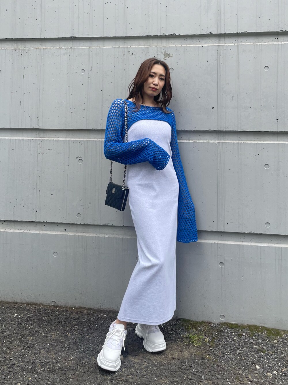 ブルー系のニット/セーター、ブラック系のショルダーバッグ、グレー系のワンピースを着用したレディースの春コーディネートの1枚目の写真