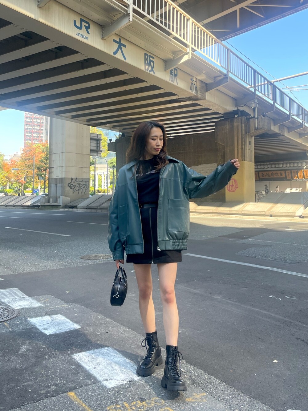 ホワイト系のショルダーバッグ、ブラック系のスカート、ブラック系のTシャツ/カットソーを着用したレディースの秋コーディネートの1枚目の写真