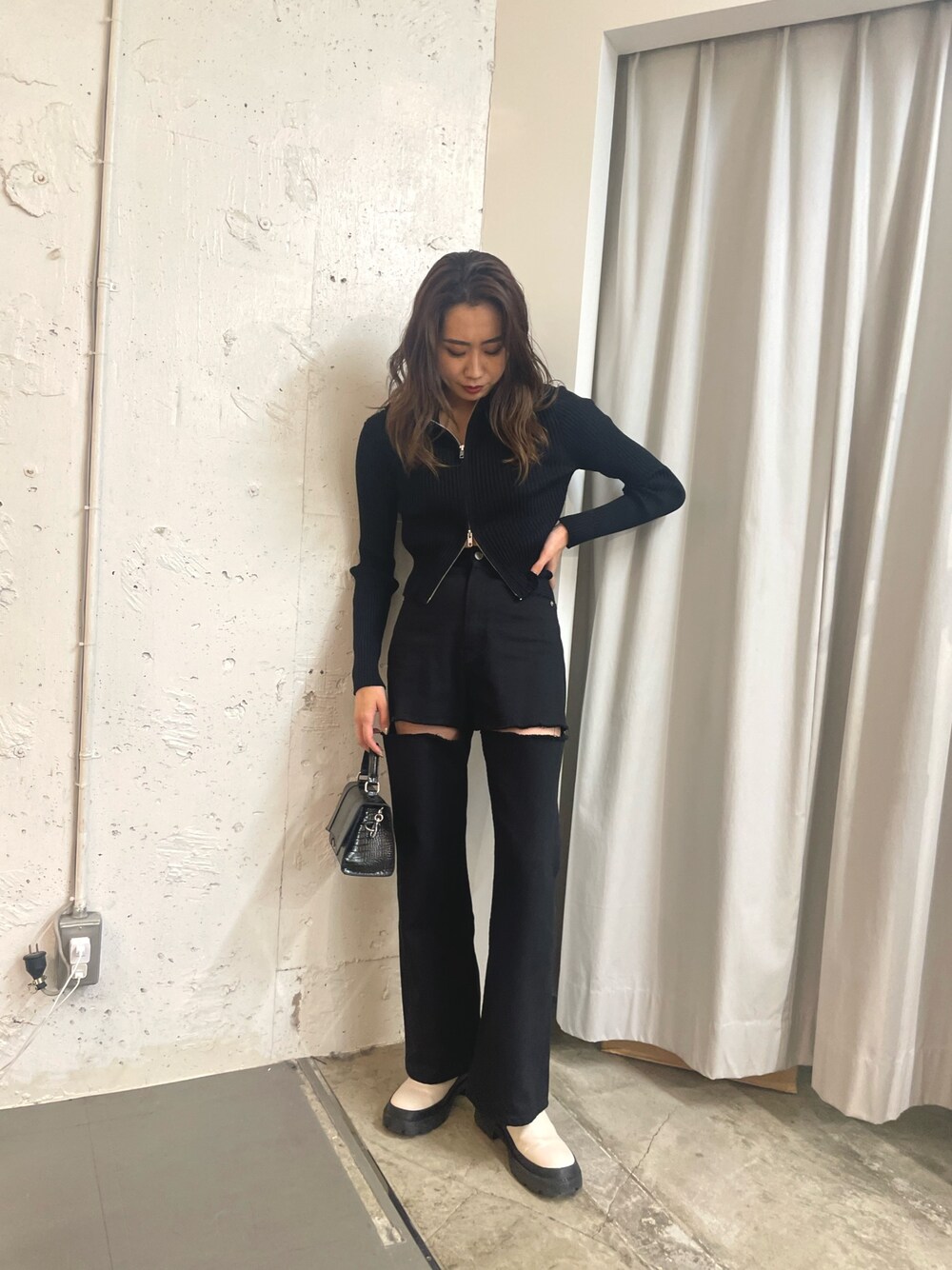 ブラック系のニット/セーター、ブラック系のショルダーバッグ、ホワイト系のブーツを着用したレディースの秋コーディネートの1枚目の写真