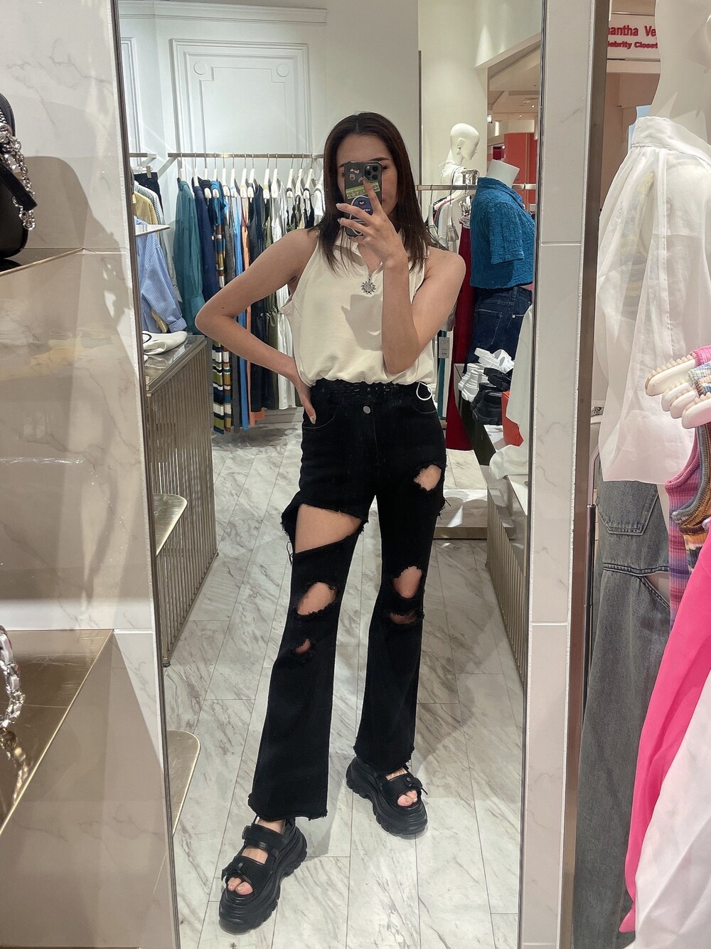 ブラック系のデニムパンツ、ブラック系のサンダル、ホワイト系のタンクトップを着用したレディースの春コーディネートの1枚目の写真