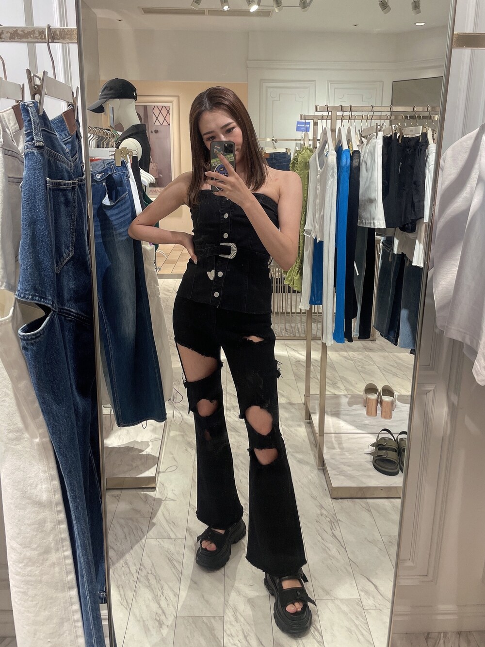 ブラック系のチューブトップ、ブラック系のデニムパンツ、ブラック系のサンダルを着用したレディースの春コーディネートの1枚目の写真