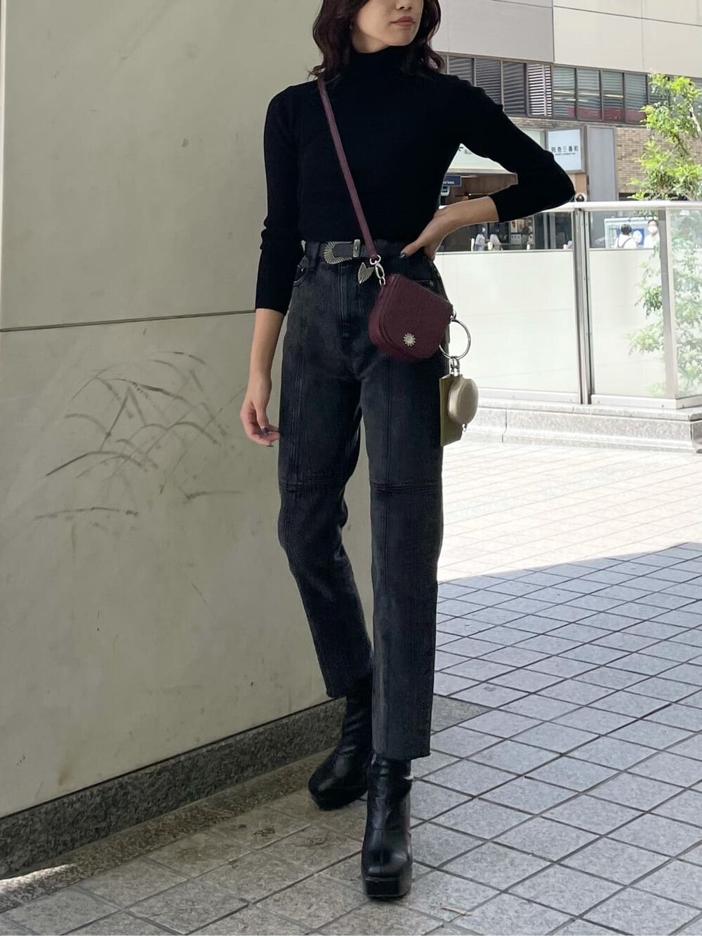 レッド系のショルダーバッグ、ブラック系のデニムパンツ、ブラック系のニット/セーターを着用したレディースの秋コーディネートの1枚目の写真