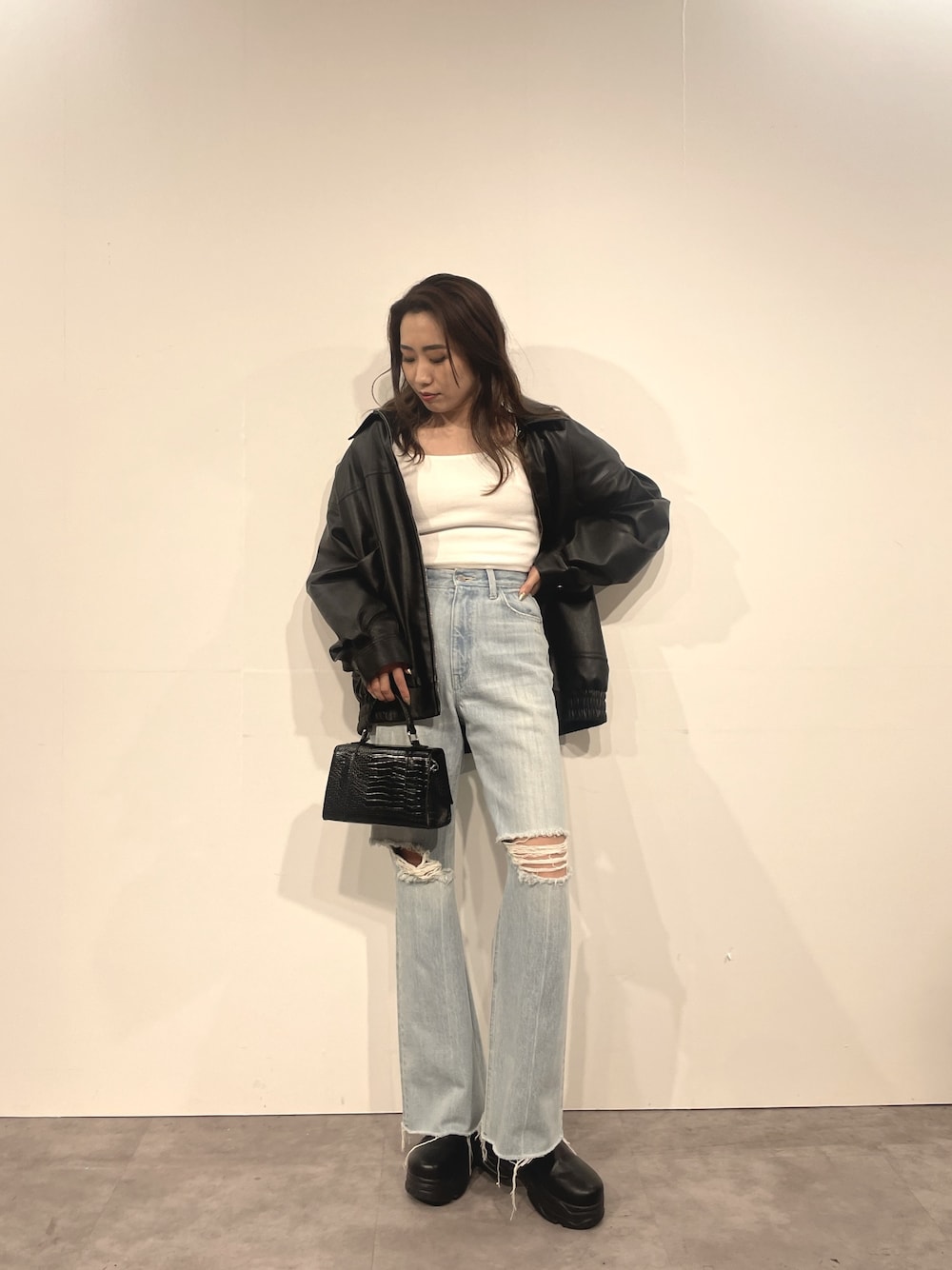 ブルー系のデニムパンツ、ブラック系のショルダーバッグ、ホワイト系のTシャツ/カットソーを着用したレディースの秋コーディネートの1枚目の写真