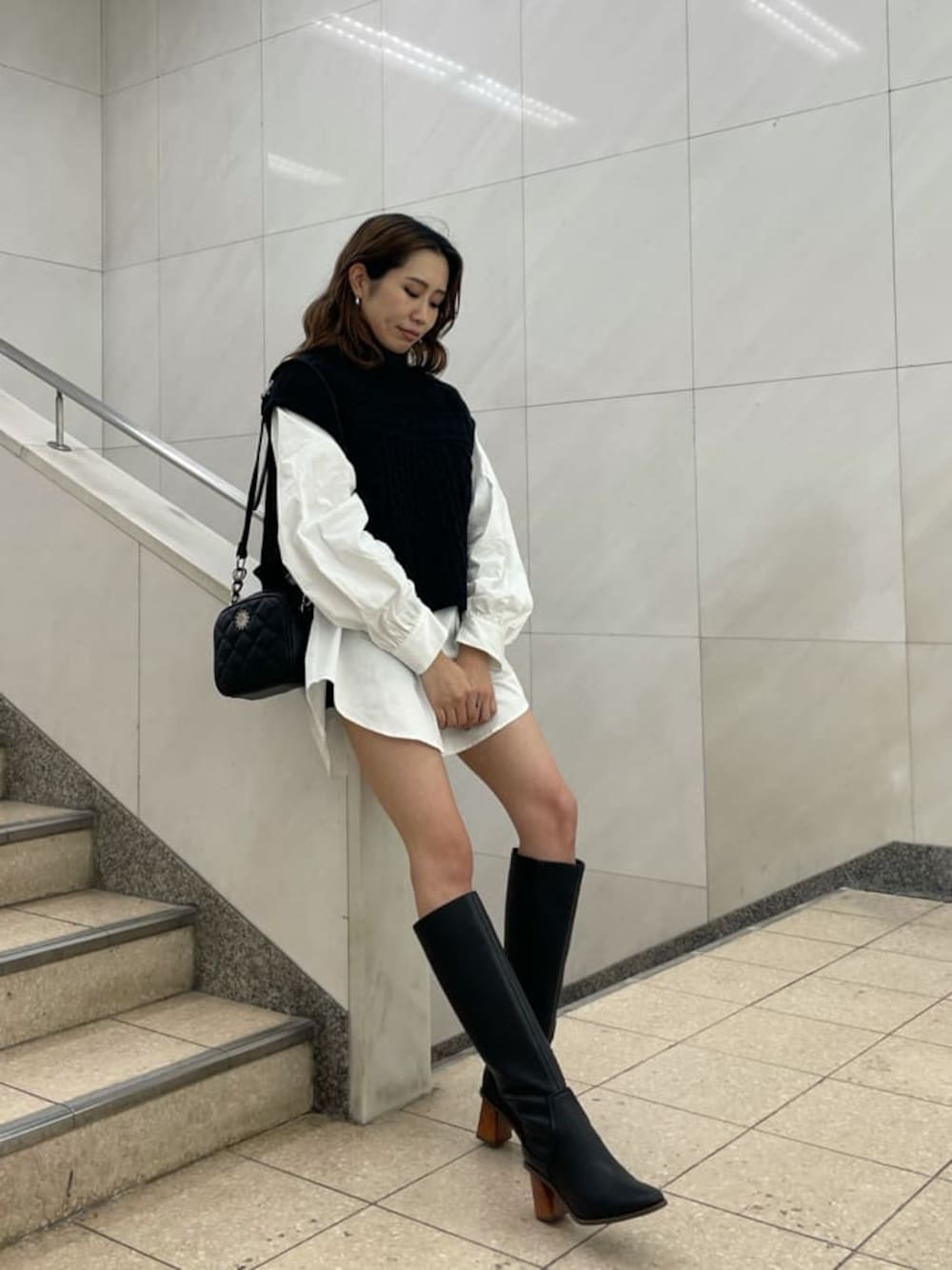 ブラック系のニット/セーター、ホワイト系のシャツ/ブラウス、ブラック系のショルダーバッグを着用したレディースの秋コーディネートの1枚目の写真