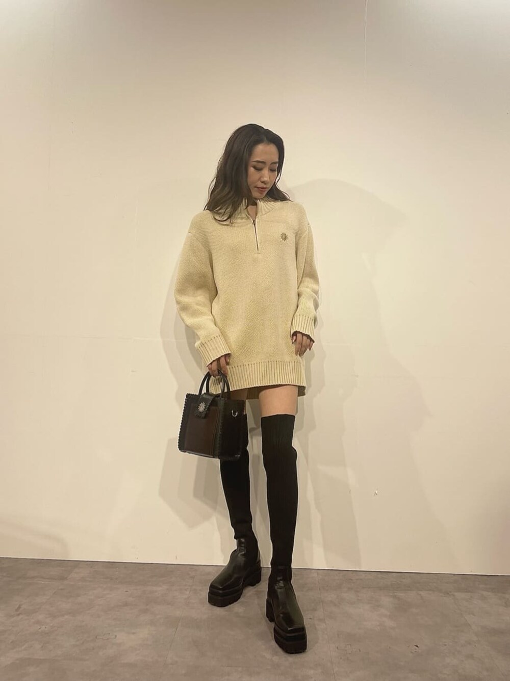 ブラック系のショルダーバッグ、ホワイト系のニット/セーター、ブラック系のブーツを着用したレディースの秋コーディネートの1枚目の写真