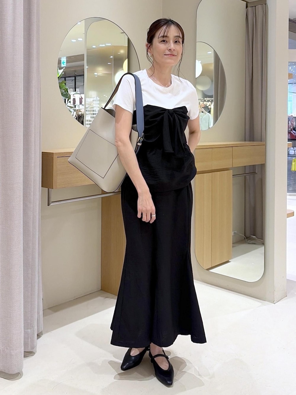 ベージュ系のトートバッグ、ブラック系のパンプス、ブラック系のTシャツ/カットソーを着用したレディースの春コーディネートの1枚目の写真