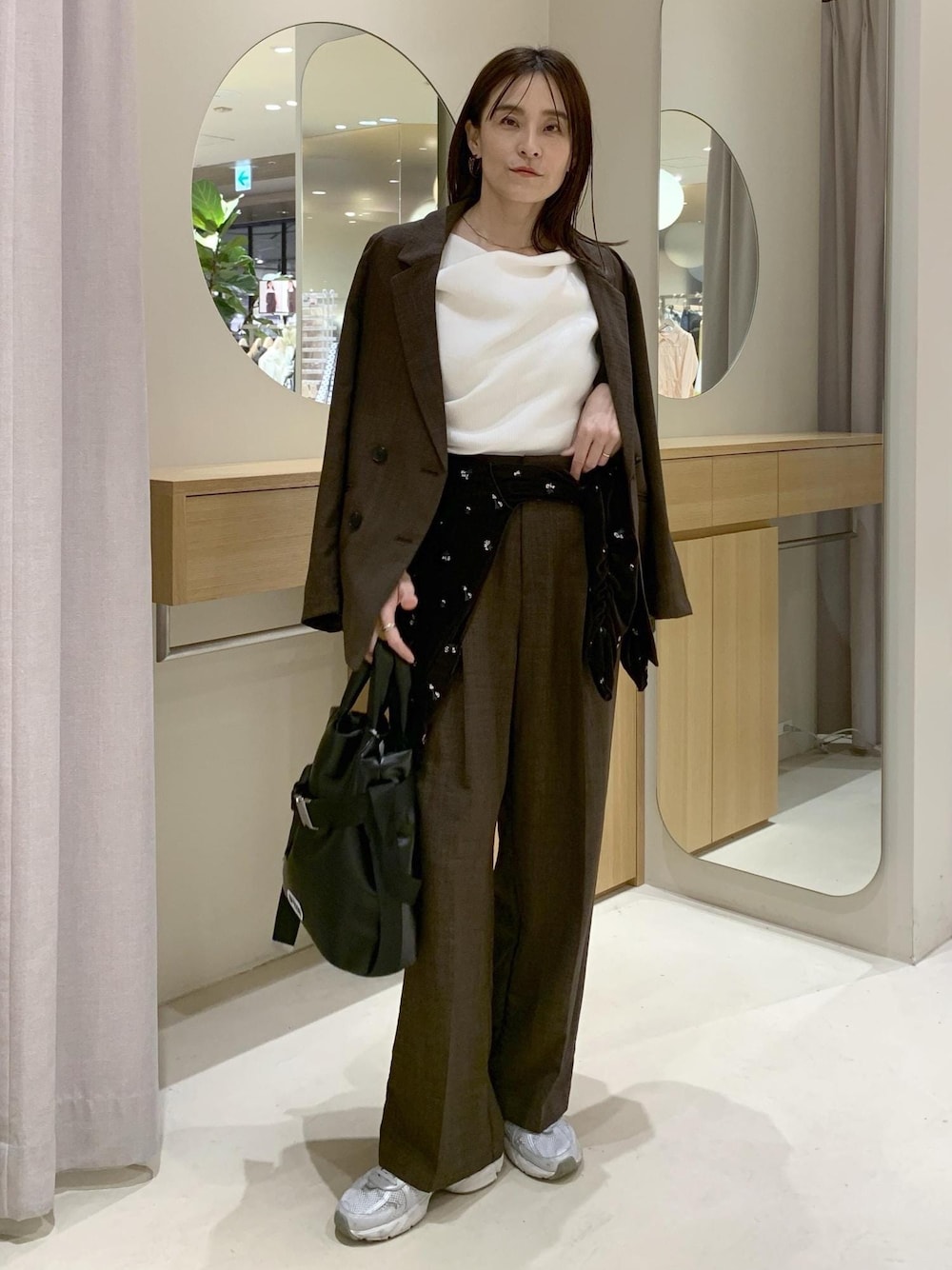 ブラック系のトートバッグ、ブラウン系のカーディガン/ボレロ、ホワイト系のニット/セーターを着用したレディースの春コーディネートの1枚目の写真