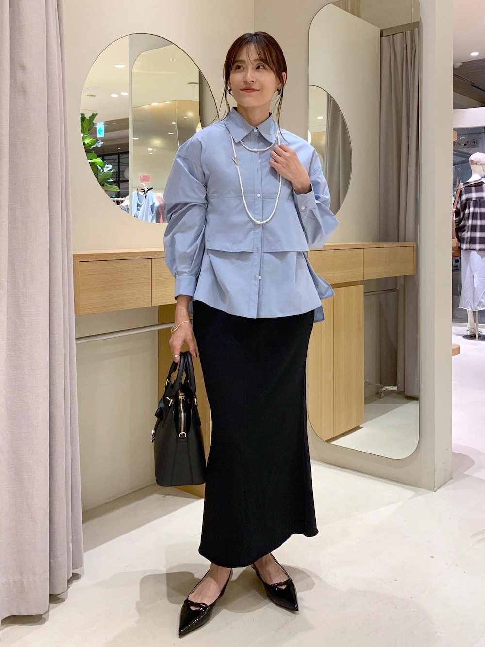 ブラック系のパンプス、ブラック系のスカート、ブルー系のシャツ/ブラウスを着用したレディースの夏コーディネートの1枚目の写真