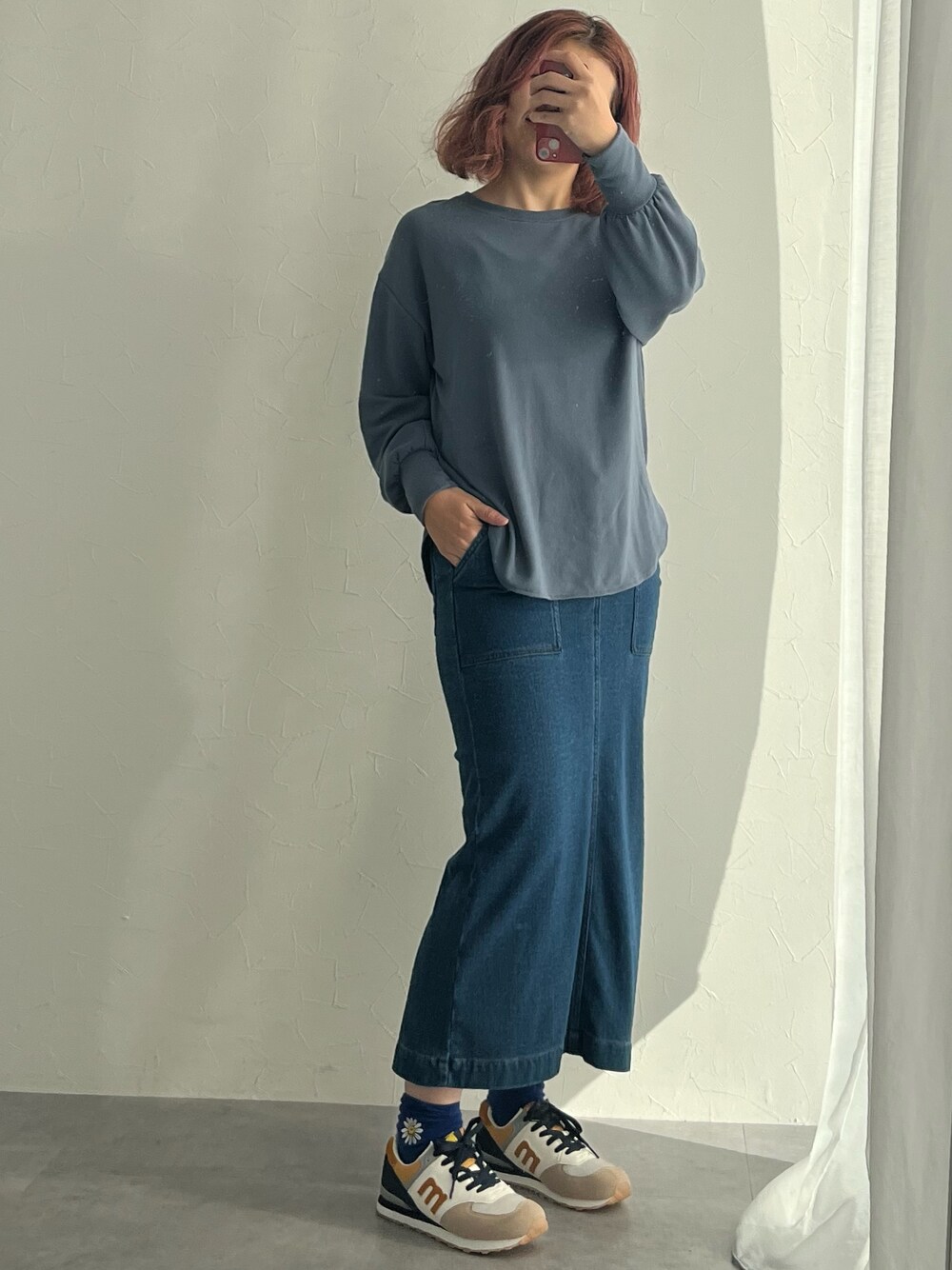 ブラック系のスニーカー、ブルー系のスカート、ホワイト系のTシャツ/カットソーを着用したレディースの秋コーディネートの1枚目の写真