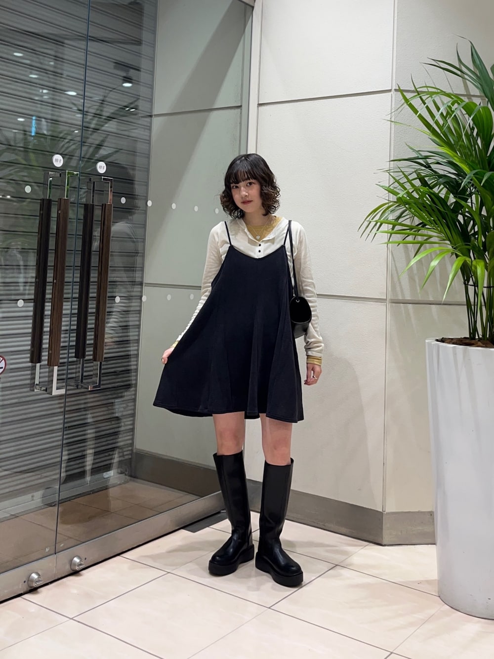 ブラック系のブーツ、グレー系のワンピース、ブラック系のショルダーバッグを着用したレディースの秋コーディネートの1枚目の写真