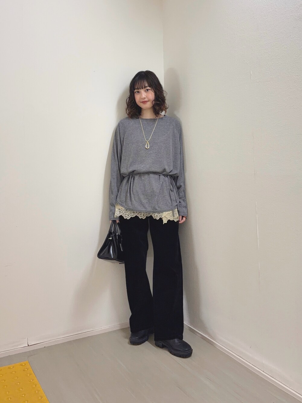 ベージュ系のキャミソール、ブラック系のデニムパンツ、ブラック系のボストンバッグを着用したレディースの冬コーディネートの1枚目の写真