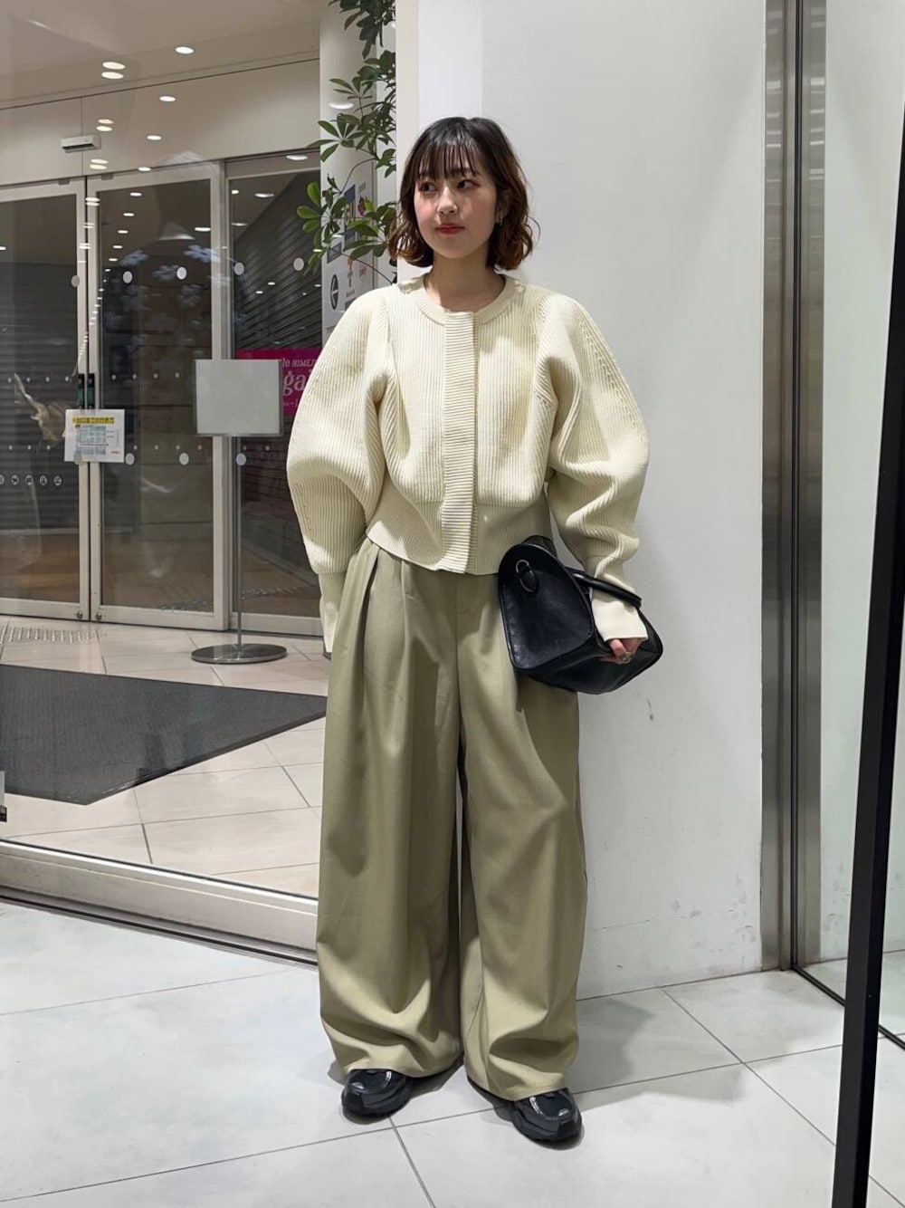 ブラック系のボストンバッグ、ベージュ系のその他パンツ、ホワイト系のカーディガン/ボレロを着用したレディースの冬コーディネートの1枚目の写真