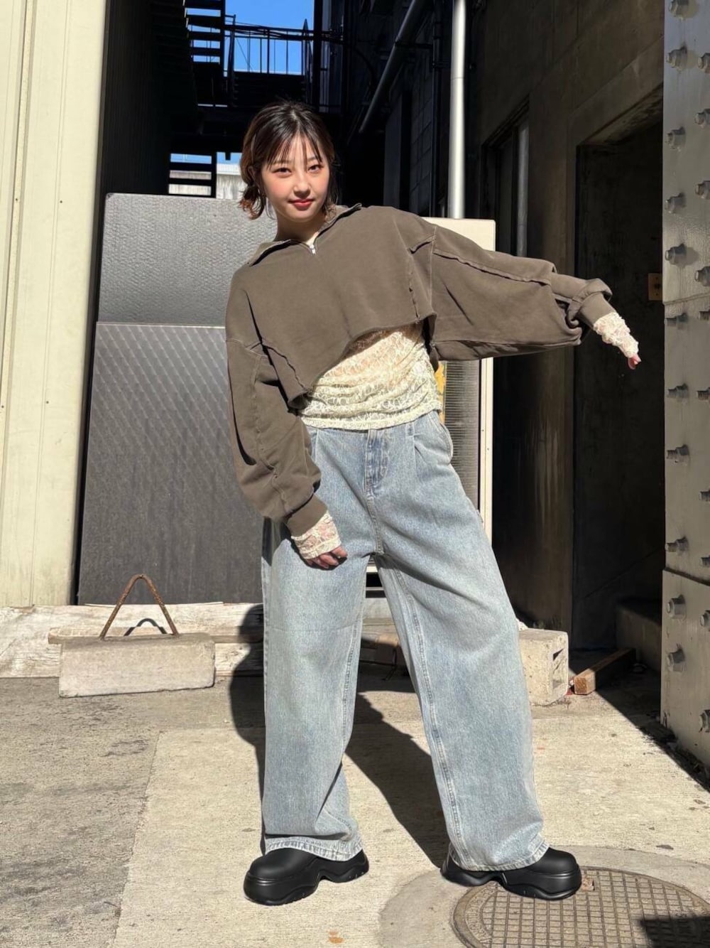 ブルー系のデニムパンツ、ベージュ系のサンダル、ブラウン系のスウェットを着用したレディースの冬コーディネートの1枚目の写真