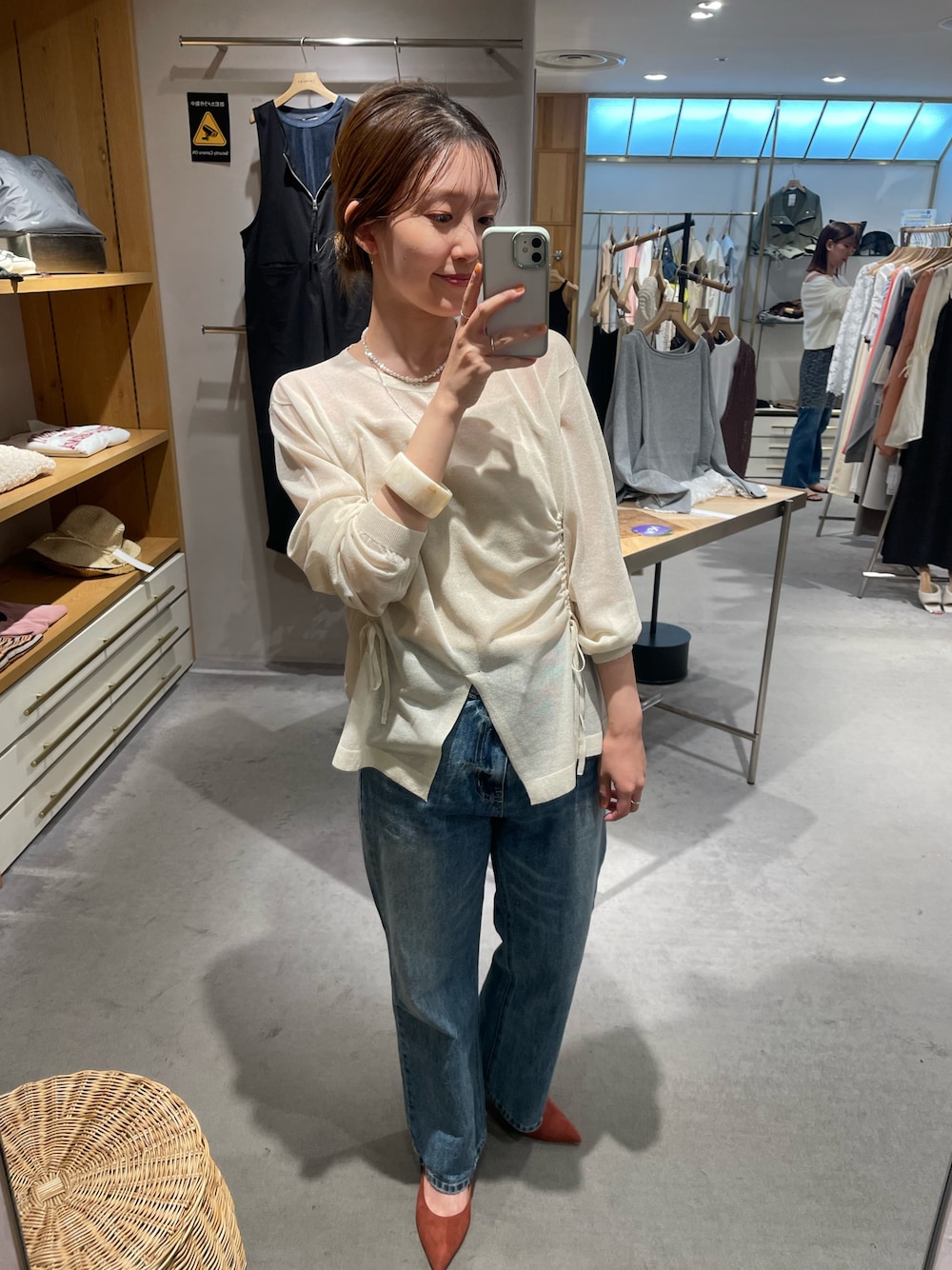 ホワイト系のニット/セーター、ベージュ系のキャミソール、ブルー系のデニムパンツを着用したレディースの秋コーディネートの1枚目の写真