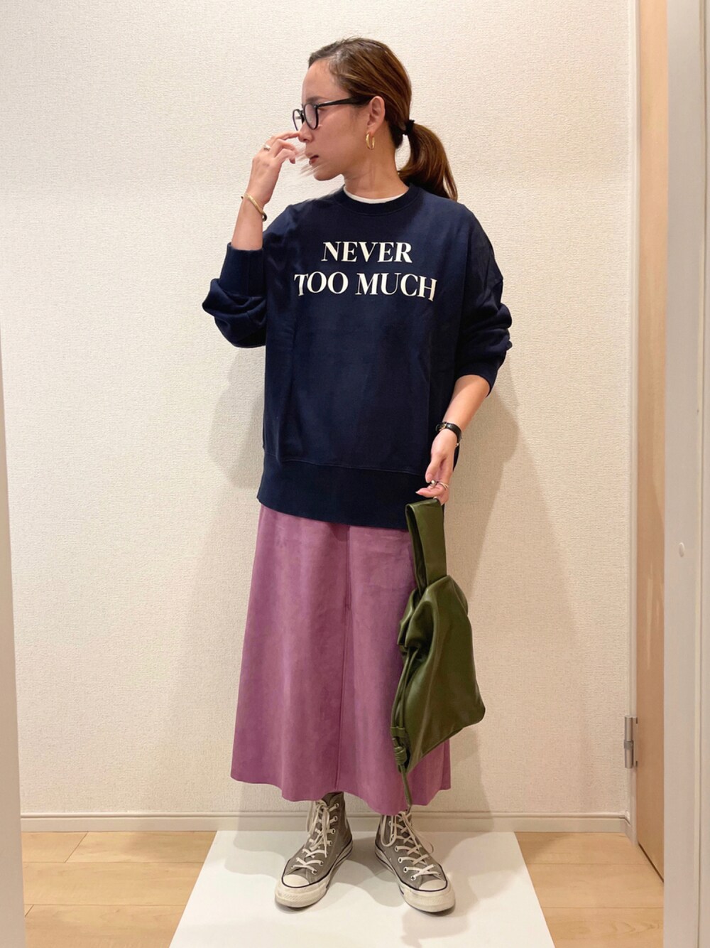 ブルー系のトップス、パープル系のスカート、グリーン系のハンドバッグを着用したレディースの秋コーディネートの1枚目の写真