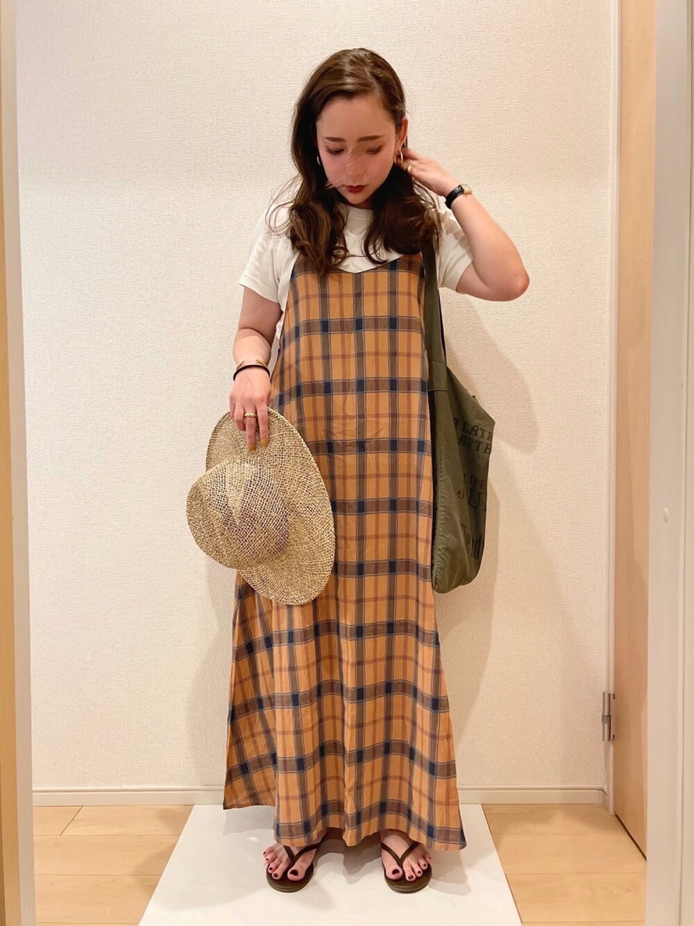 グリーン系のトートバッグ、ブラウン系のサンダル、オレンジ系のワンピースを着用したレディースの春コーディネートの1枚目の写真