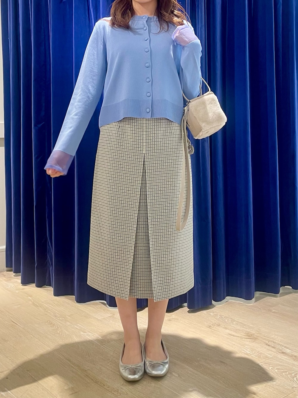 ブルー系のカーディガン/ボレロ、ベージュ系のショルダーバッグ、ブラック系のスカートを着用したレディースの秋コーディネートの1枚目の写真