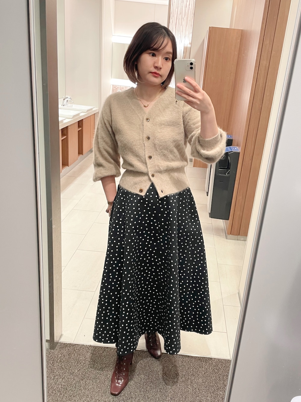 ベージュ系のカーディガン/ボレロ、その他のスカート、ブラウン系のブーツを着用したレディースの秋コーディネートの1枚目の写真