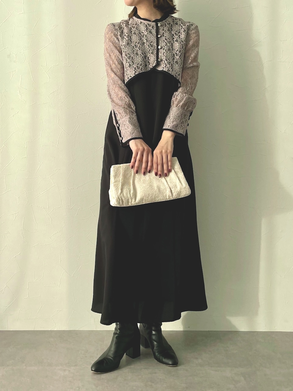 ブラック系のドレス、ゴールド系のクラッチバッグを着用したレディースの冬コーディネートの1枚目の写真