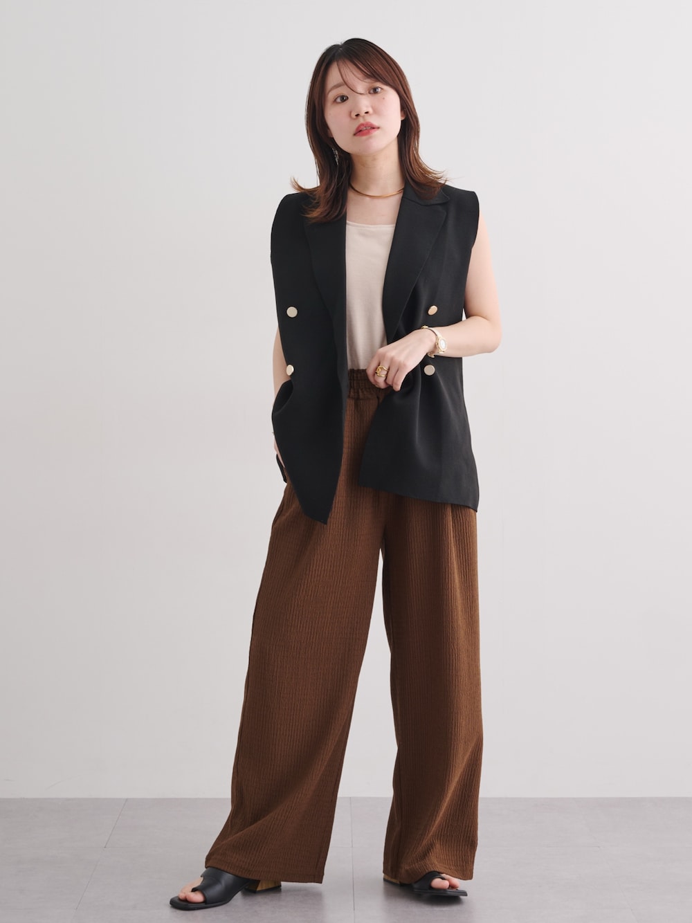 ブラック系のニット/セーター、ブラウン系のパンツを着用したレディースの春コーディネートの1枚目の写真