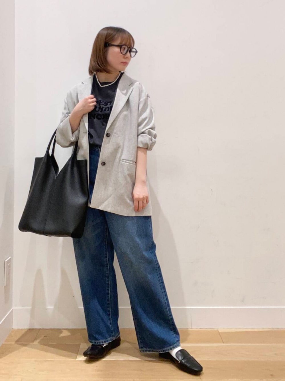 ブラック系のローファー、ブルー系のデニムパンツ、ブラック系のトートバッグを着用したレディースの春コーディネートの1枚目の写真