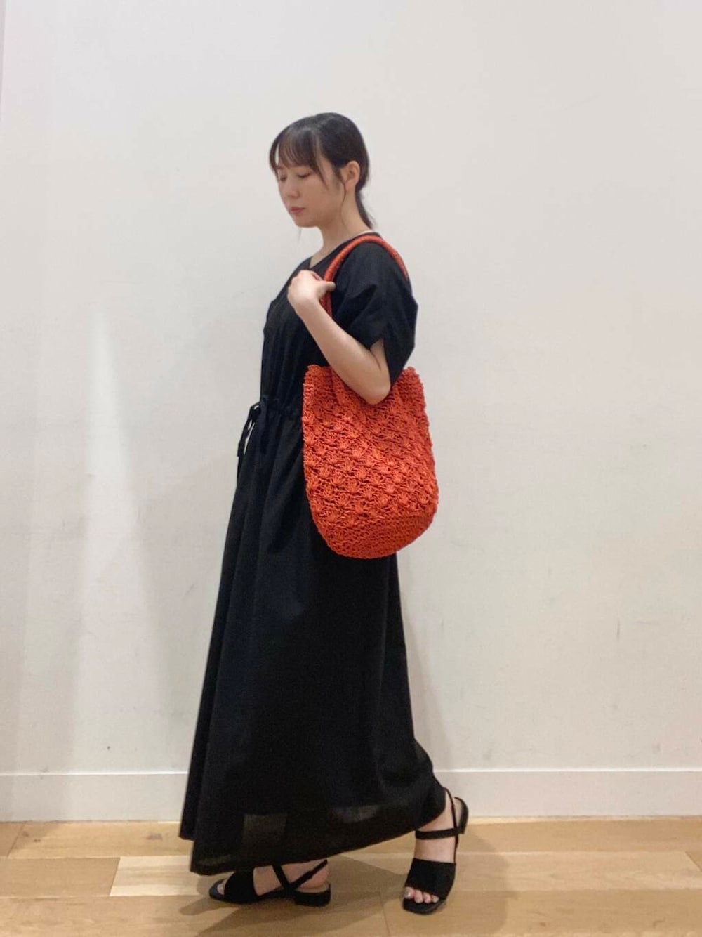 オレンジ系のトートバッグ、ブラック系のワンピース、ブラック系のサンダルを着用したレディースの夏コーディネートの1枚目の写真