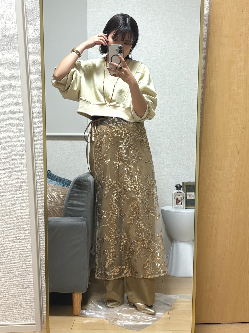 ベージュ系のスラックス、ゴールド系のスカート、ゴールド系のサンダルを着用したレディースの冬コーディネートの1枚目の写真