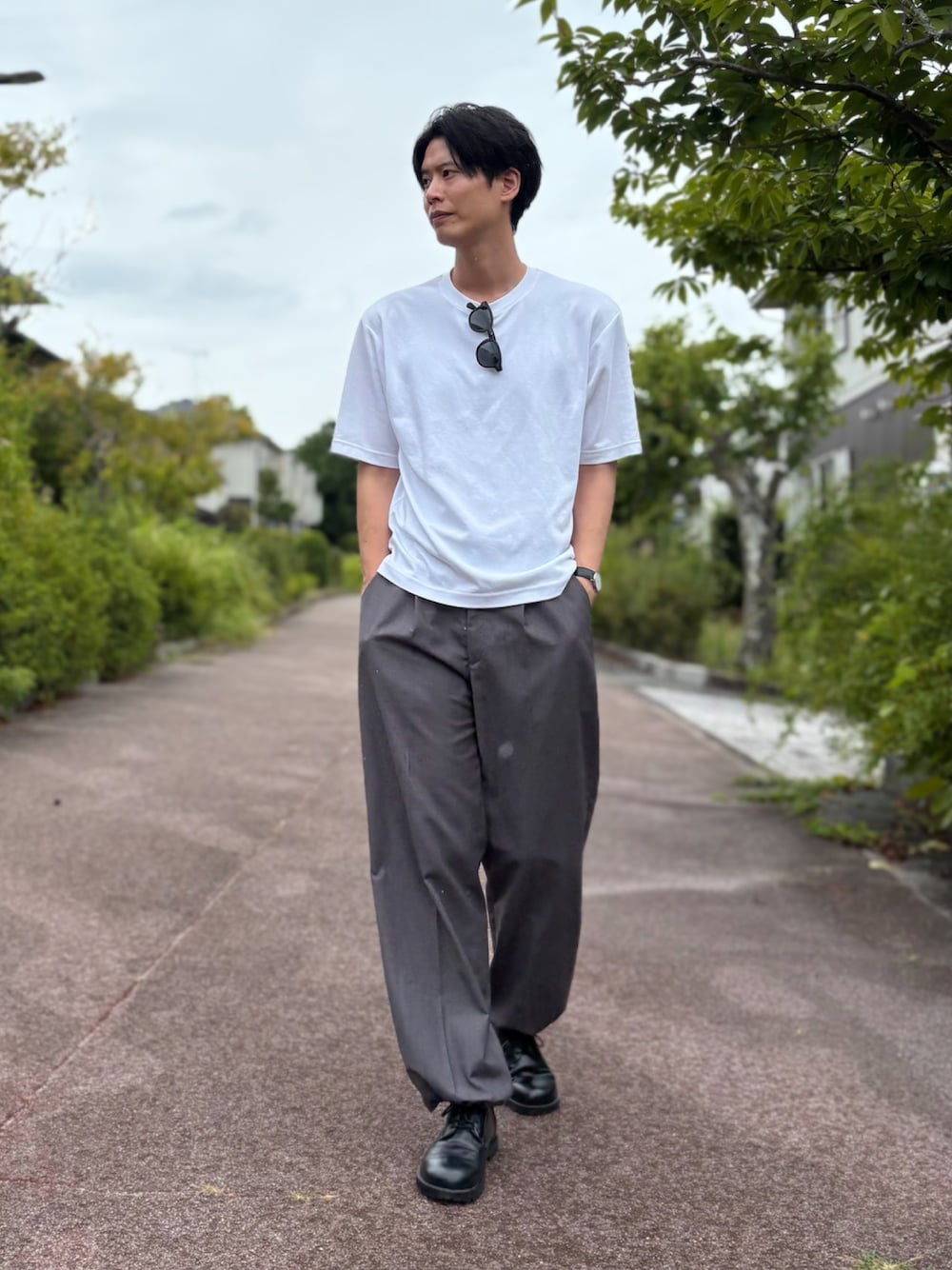 ホワイト系のTシャツ/カットソー、グレー系のスラックス、ブラック系のドレスシューズを着用したメンズの夏コーディネートの1枚目の写真