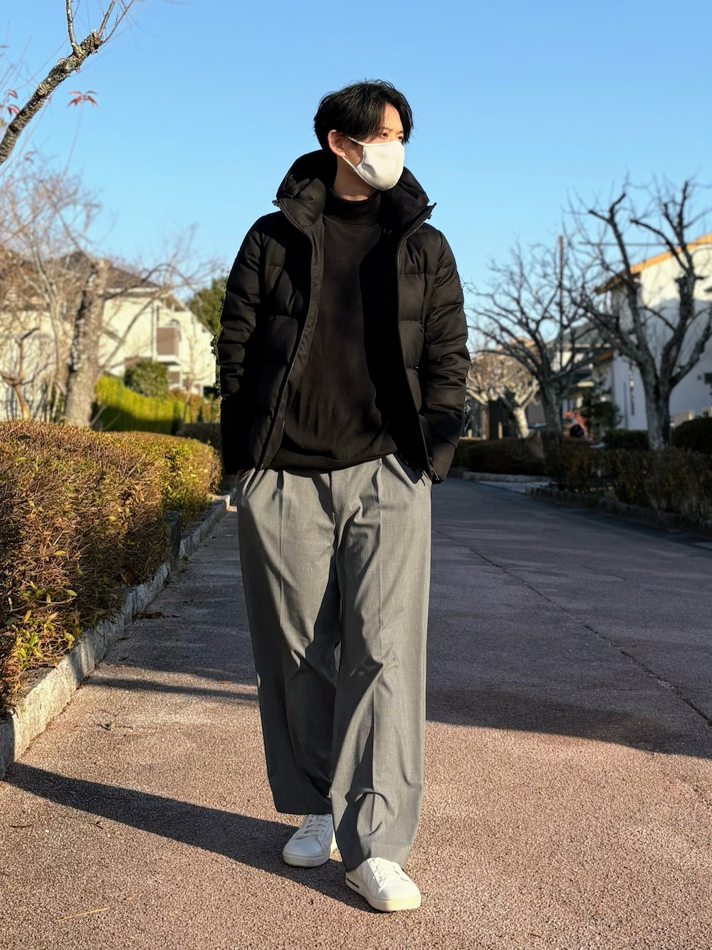 ホワイト系のスニーカー、ブラック系のニット/セーター、ブラック系のダウンジャケット/コートを着用したメンズの冬コーディネートの1枚目の写真