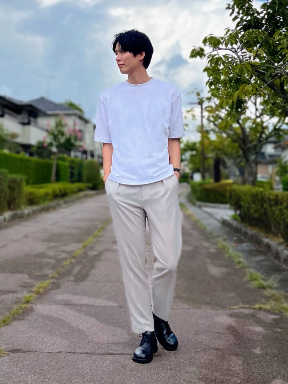 グレー系のスラックス、ブラック系のドレスシューズ、ホワイト系のTシャツ/カットソーを着用したメンズの夏コーディネートの1枚目の写真