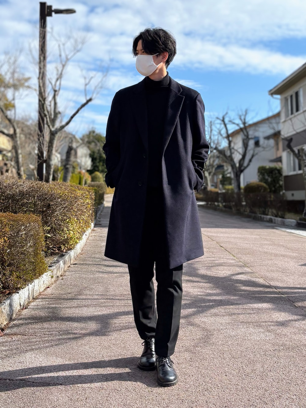 ブラック系のドレスシューズ、ブラック系のニット/セーター、ブルー系のチェスターコートを着用したメンズの冬コーディネートの1枚目の写真