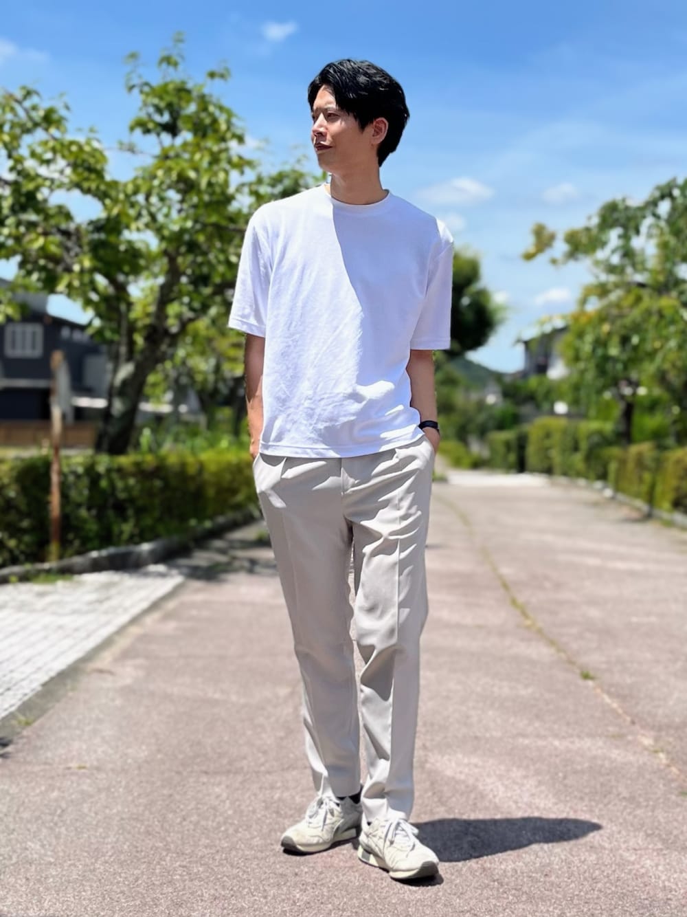 グレー系のスラックス、グレー系のスニーカー、ホワイト系のTシャツ/カットソーを着用したメンズの夏コーディネートの1枚目の写真